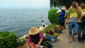 Cina, dintorni di Dali. Turisti e venditrici di frutta lungo la riva del lago Erhài.