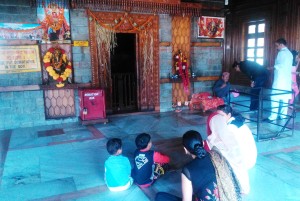 Old Manali, Manu Temple, un sacerdote riceve i fedeli, mentre altri pregano. Sulla porta dell'altare dedicato a Manu sono appese delle spighe di grano.